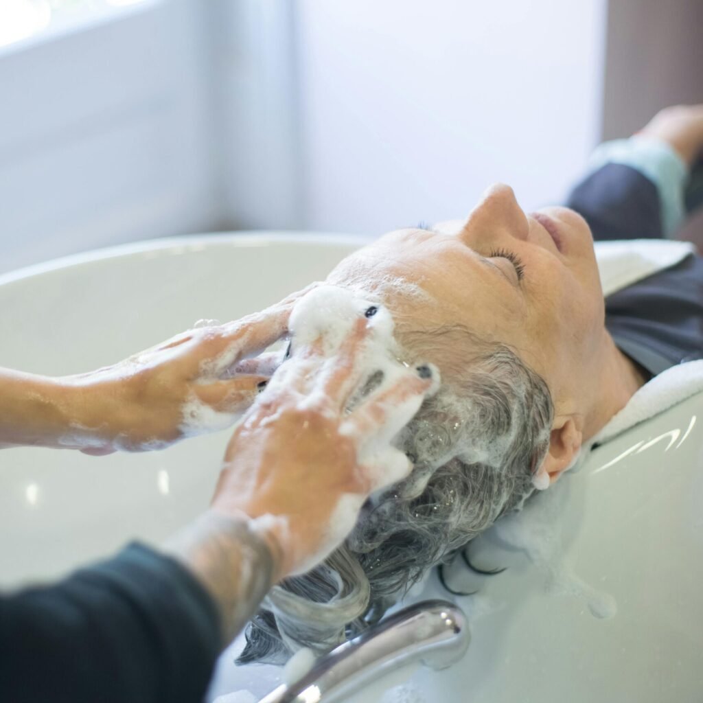 Close-up of senior woman getting hair washed with foam at salon sink, enjoying the pampering session.